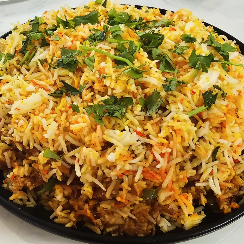 A close-up of Indo-Pak Flavors NYC's chicken biryani, garnished with fresh green cilantro.