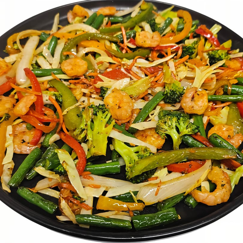 Colorful Indian stir-fry with shrimp, broccoli, bell peppers, onions, and green beans on a black plate.